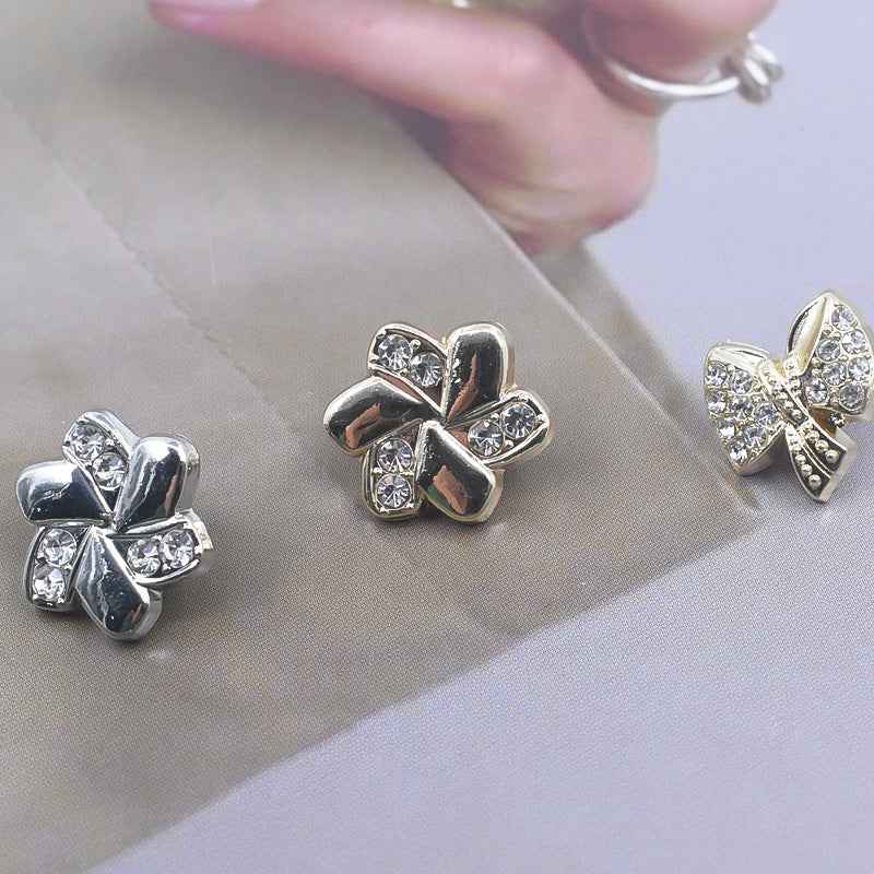 Rhinestone shirt buttons held in hand: silver and gold bow designs