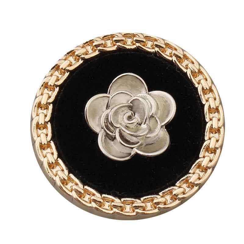 Round black-faced button, gold rim and chain, silver flower center, metal shank.