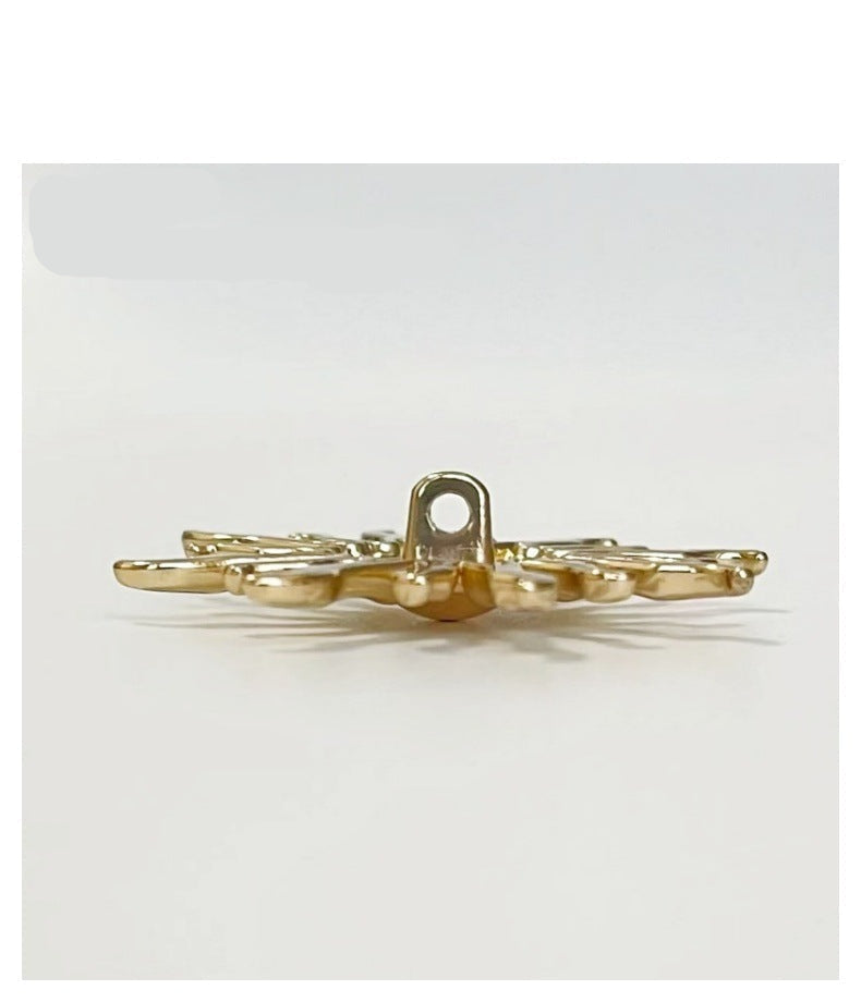 Gold-tone sun-shaped metal shank button, side view with sewing loop