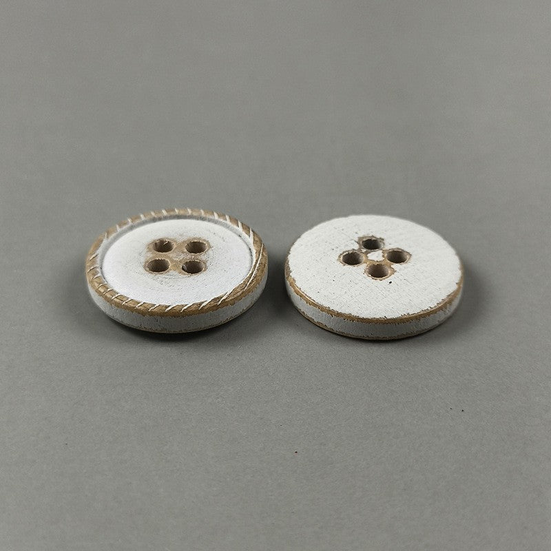 Two white round flat 4-hole wood buttons with distressed brown edges