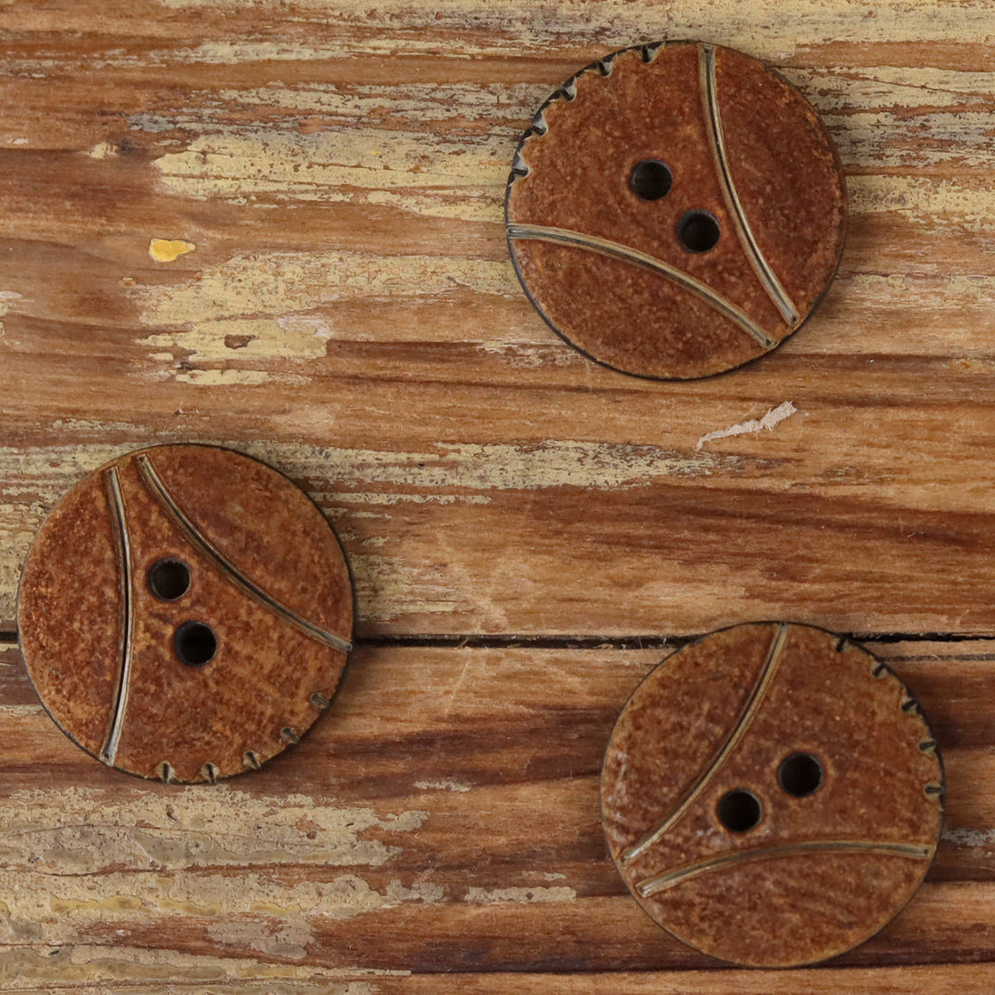 Round 2-hole horn button with scorched finish, two holes and dark curved grooves