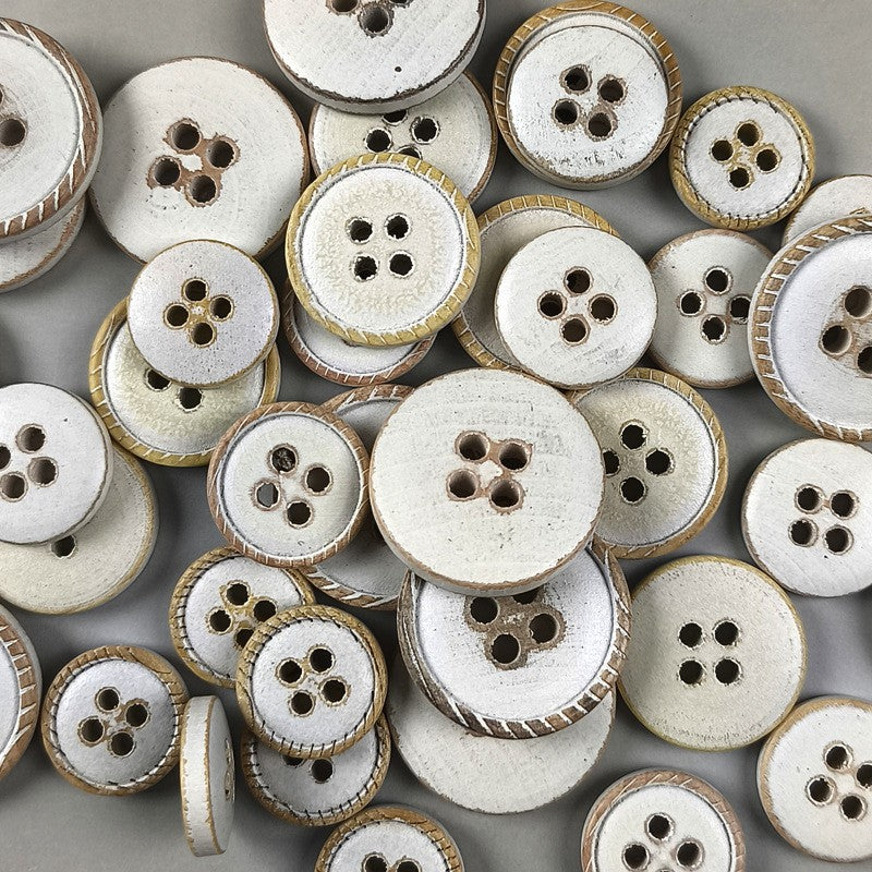 Pile of white round flat 4-hole wood buttons with distressed brown edges