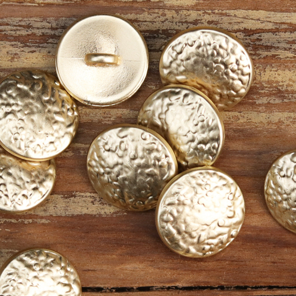 Round metal shank buttons with vintage wave embossing in light gold and pale metallic tones.