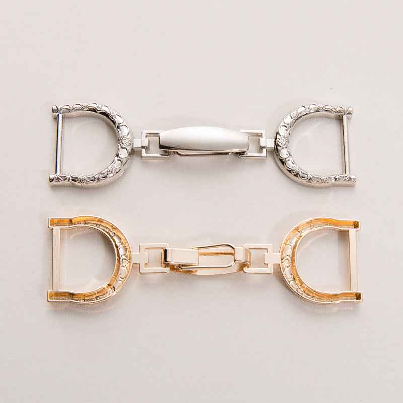Oversized metal belt buckle clasp pair with central bar; silver-tone and gold-tone views shown