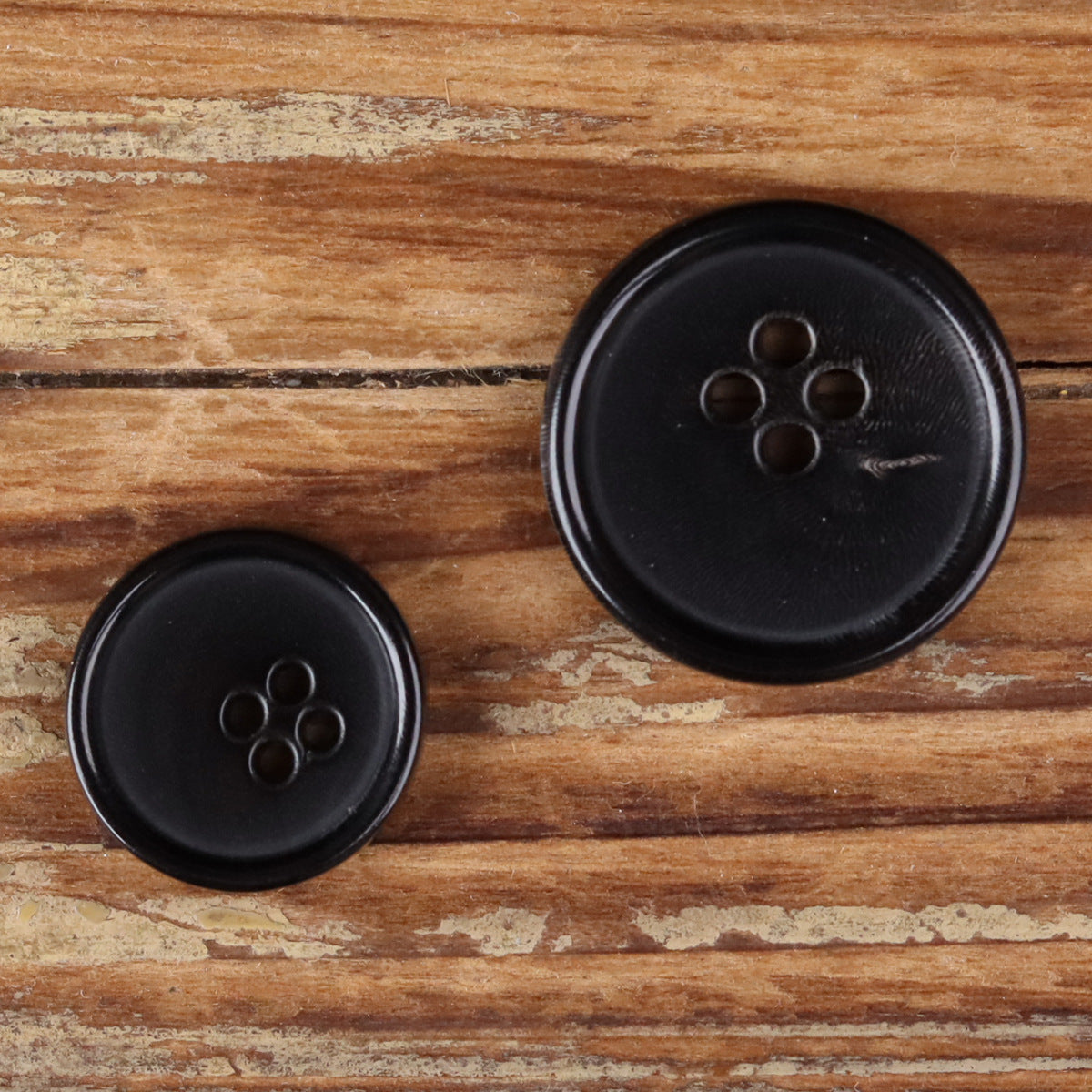 Two black 4-hole round buttons shown side by side