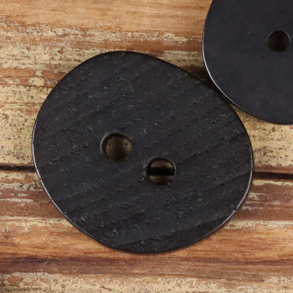 Dark natural 2-hole button with two holes, irregular round shape, close-up.