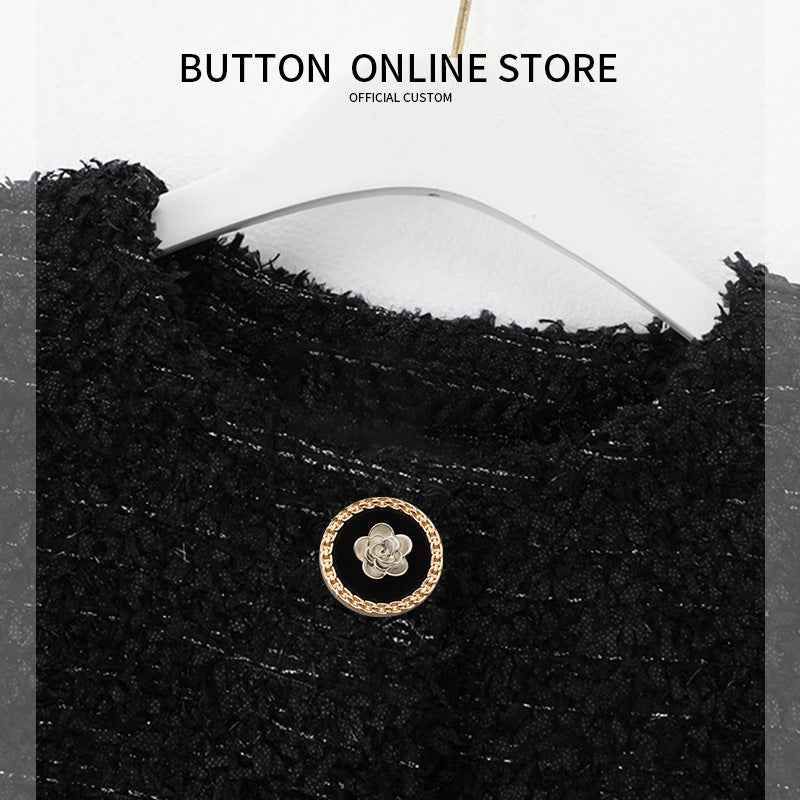 Round button on black fabric: gold border, silver flower center, metal shank.