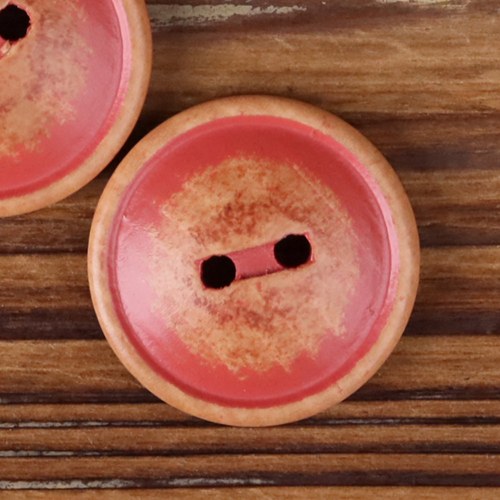 Round red wood 2-hole button with two dark holes, close-up