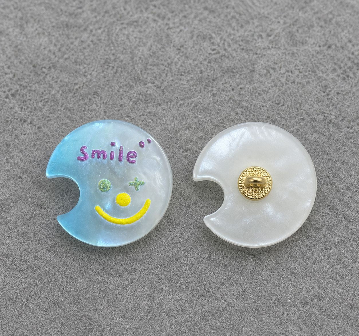 Blue moon-shaped resin shank button with colorful smiley face; gold back shank detail