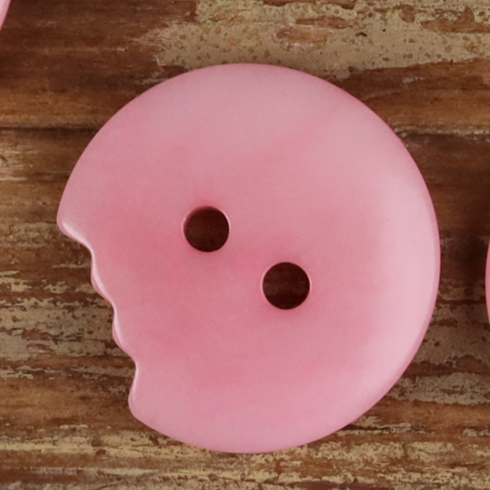 Pink irregular seed button with two holes and a natural scalloped edge.