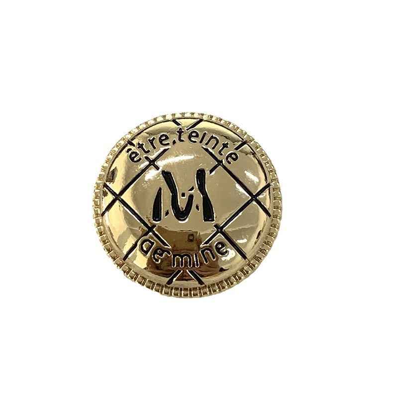 Gold round metal button with engraved M design, beaded edge and cross pattern