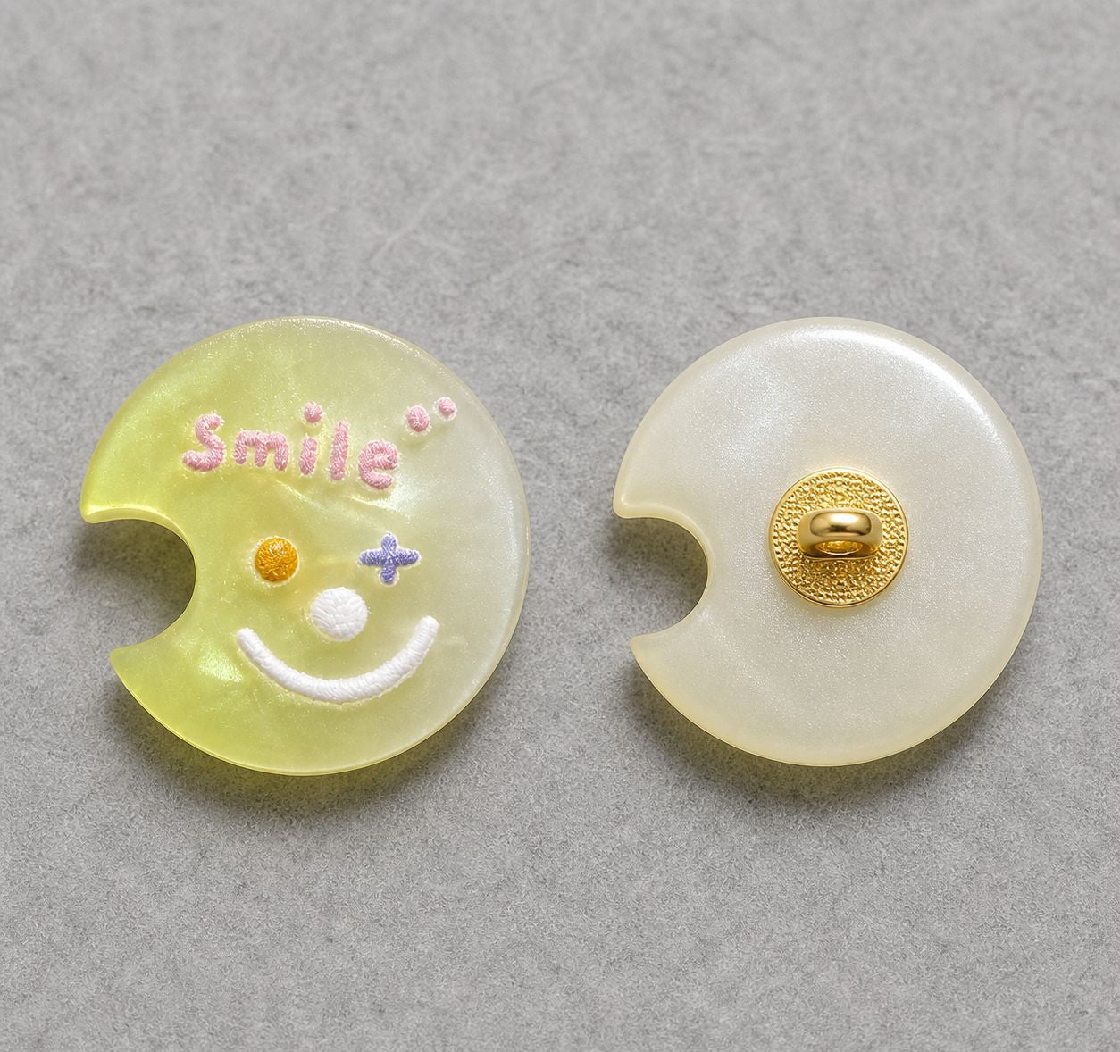 Lime green moon-shaped resin shank button with colorful smiley face; gold back shank detail