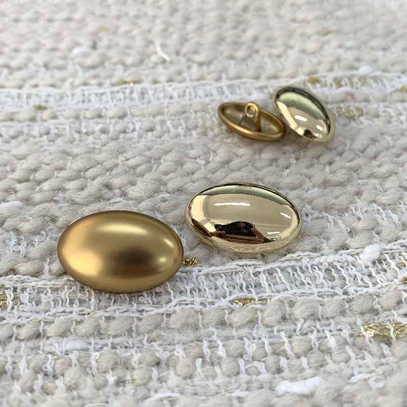Oval gold alloy shank buttons set, front and back views on fabric