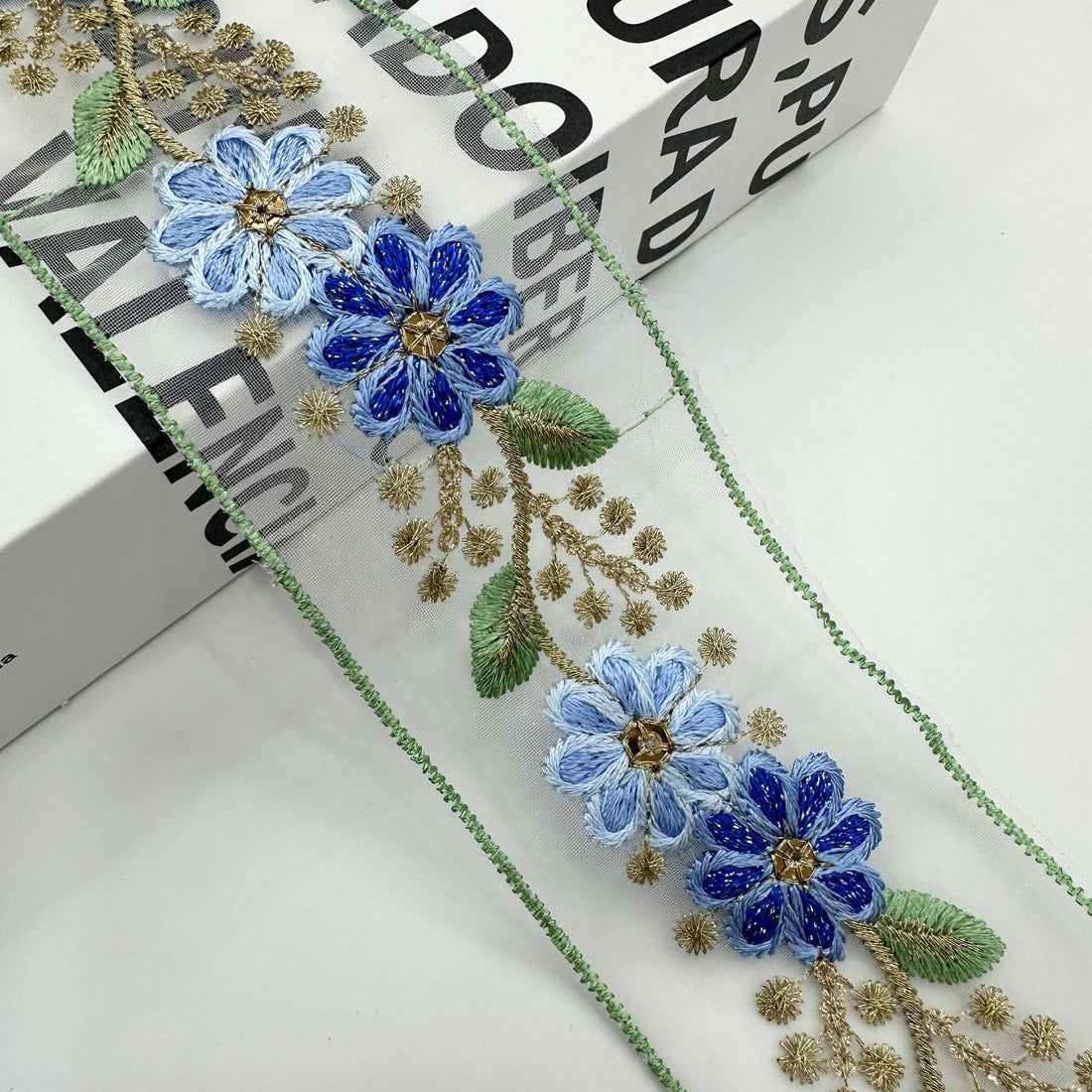Ethnic organza lace trim with purple, blue flowers and gold thread on pale fabric