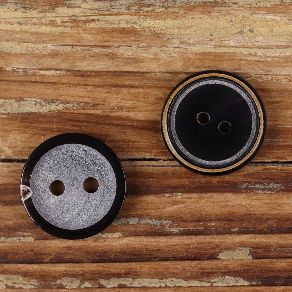 Two-hole round black and gray horn buttons with burnt-edge trim