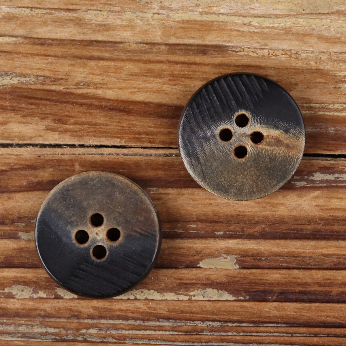 Set of two black 4-hole flat buttons with horn-grain texture and matte finish