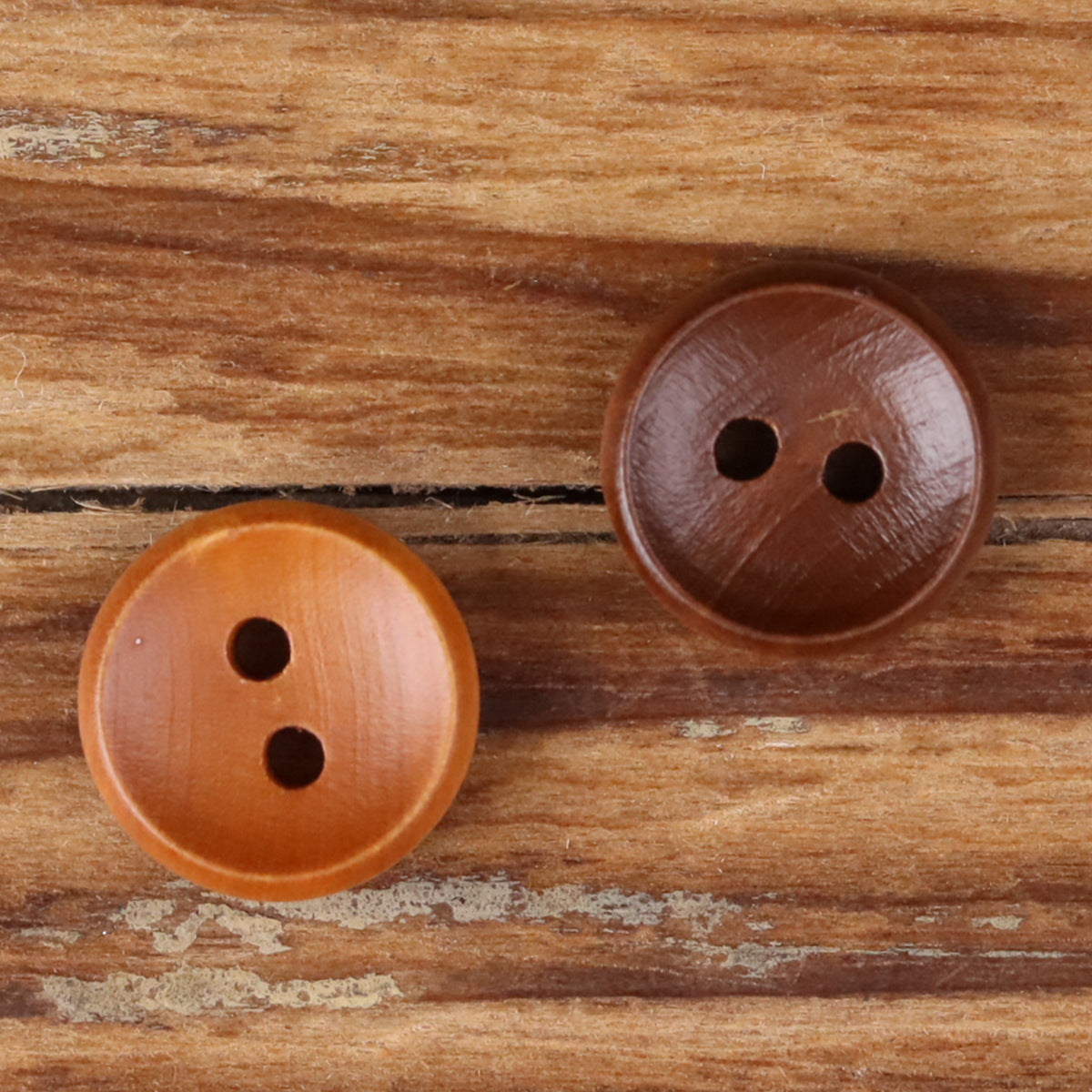 Two round 2-hole wood buttons, light orange-brown and dark brown.