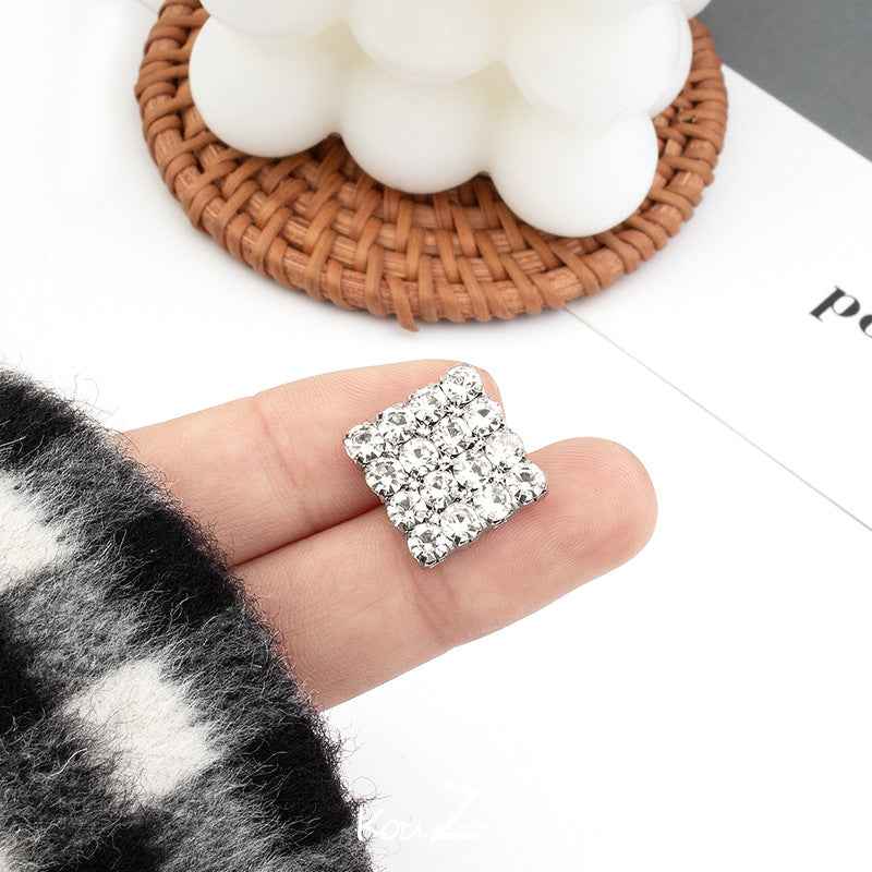 Silver diamond-cut square rhinestone metal button, held in hand
