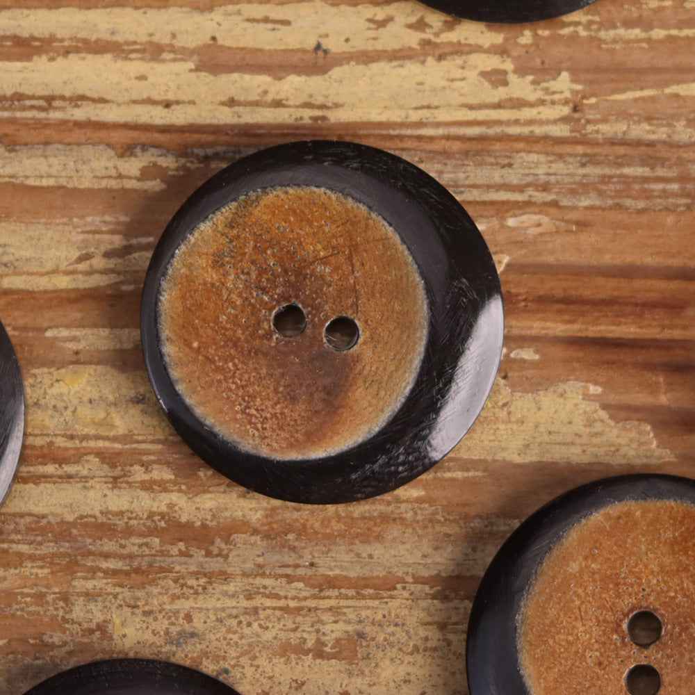 Hand-carved 2-hole horn button, mustard yellow center, dark rim, floral detail