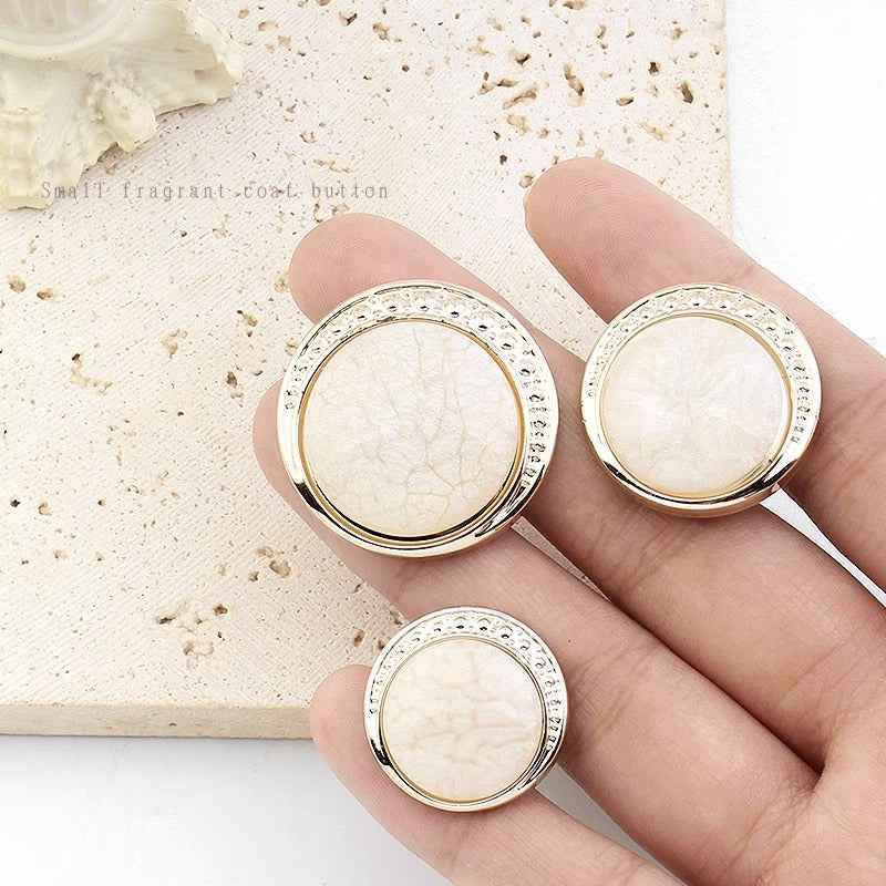 Round resin shank buttons, cream color, three visible with silver-tone textured rim and shanks