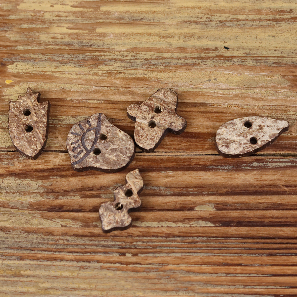Light coconut shell novelty buttons with two holes each in several whimsical shapes