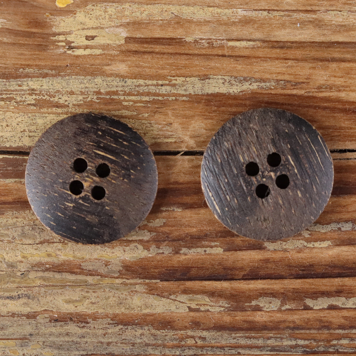 Pair of round dark wood buttons with four-hole design, distressed finish.