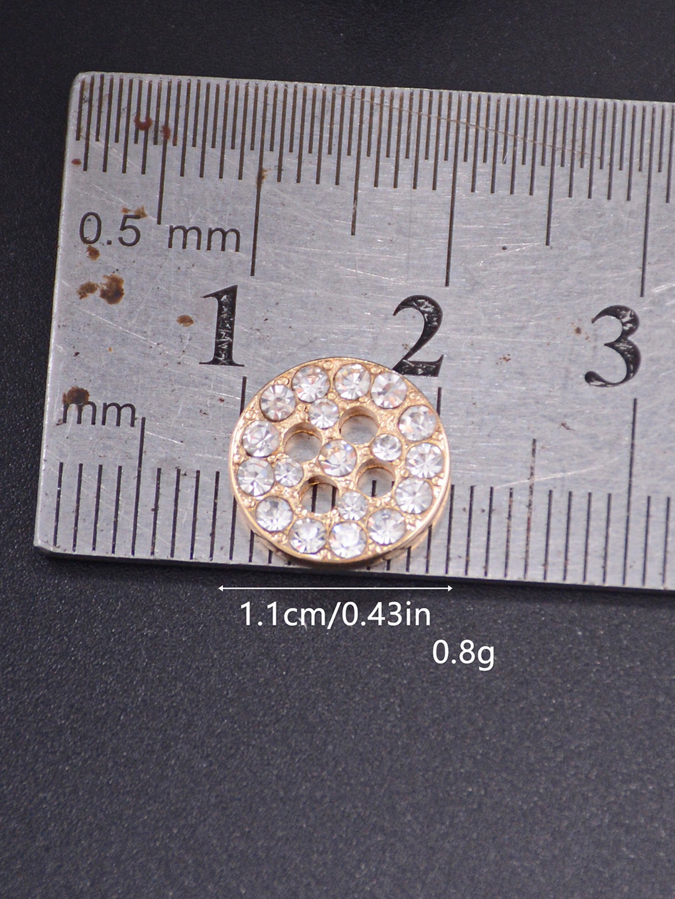 Gold round rhinestone 4-hole shirt button shown beside a ruler for size