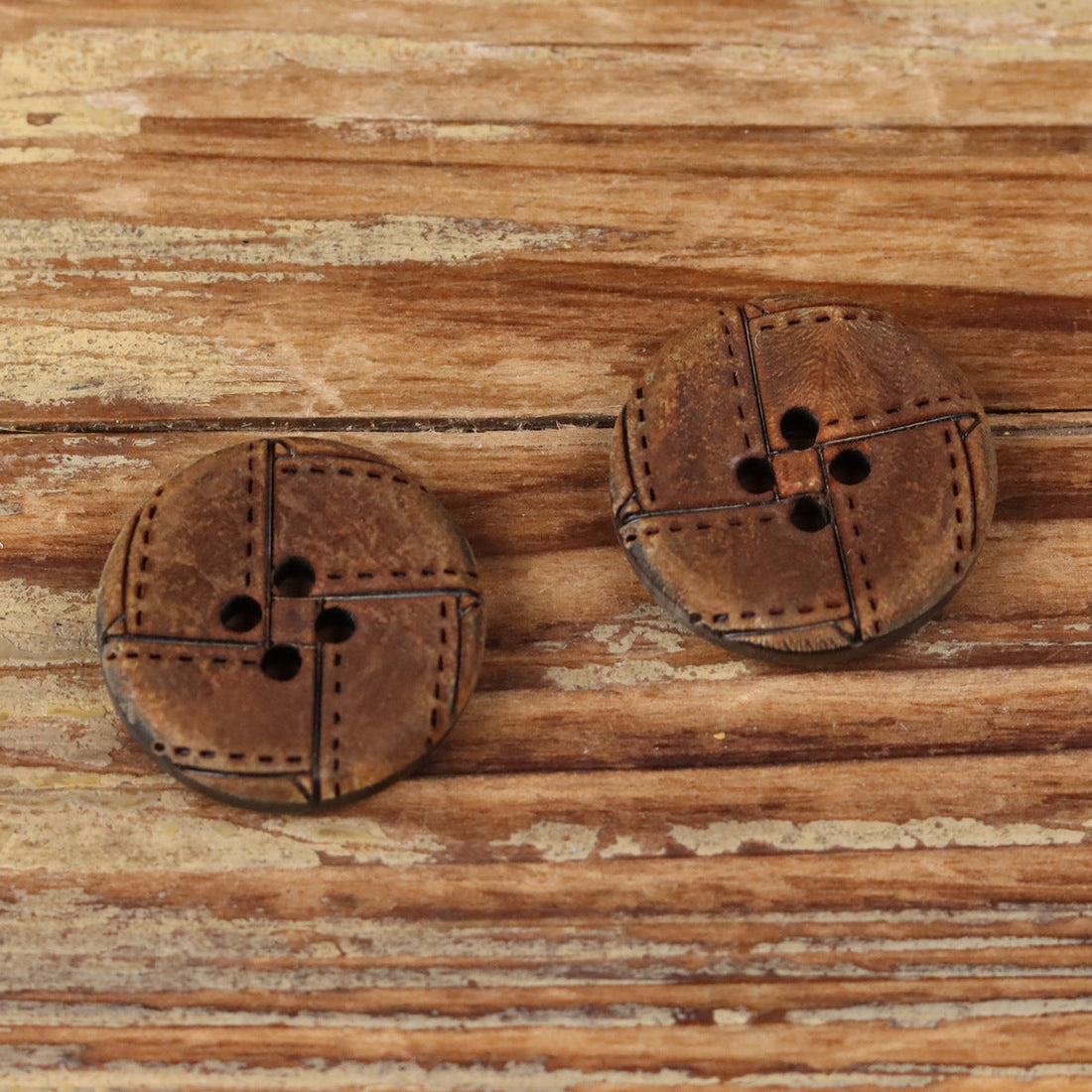 Round 4-hole horn button with geometric engraved design and dark stitched lines