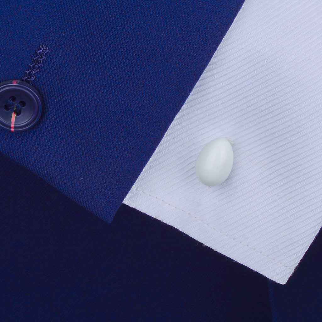 White egg-shaped cufflinks on a dress shirt cuff