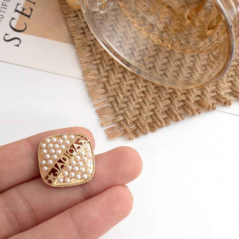 Gold square metal button with pearl-style studs and decorative geometric cutout