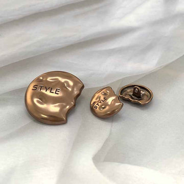 Gold semi-circular metal shank buttons, engraved “STYLE” on face and shank loop