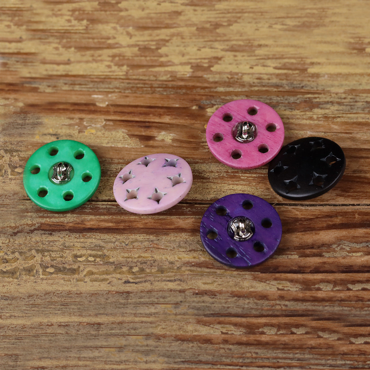 Five star-cutout horn shank buttons in green, pink, black, and purple with metal shanks