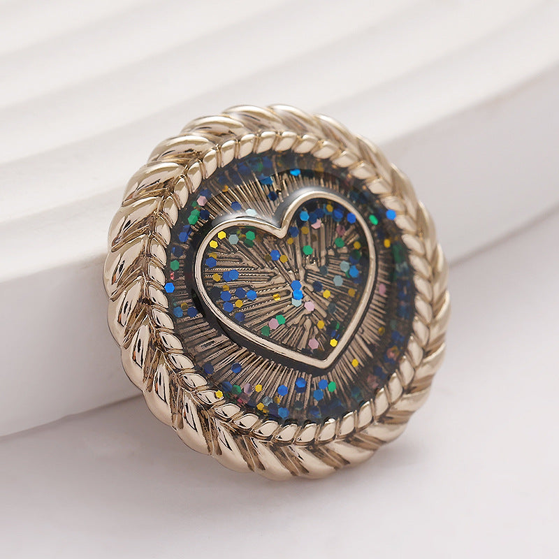 Gold heart-shaped metal shank button with braided rim and glitter mosaic center