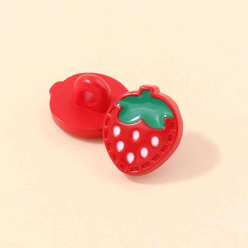 Red strawberry-shaped plastic shank button, side view with green leaf and white dots
