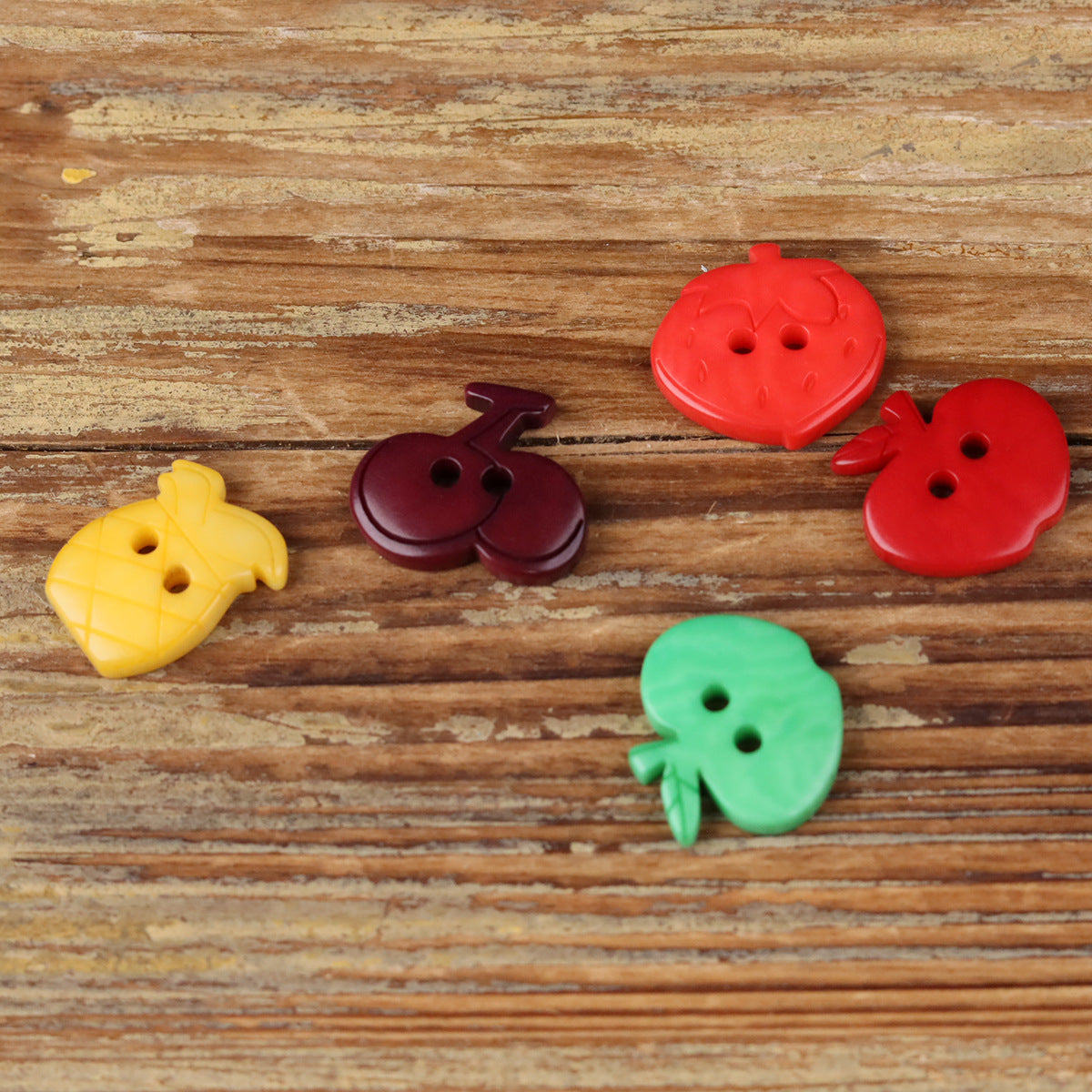 Fruit-shaped corozo buttons, red, green, yellow, and dark purple, assorted fruit shapes