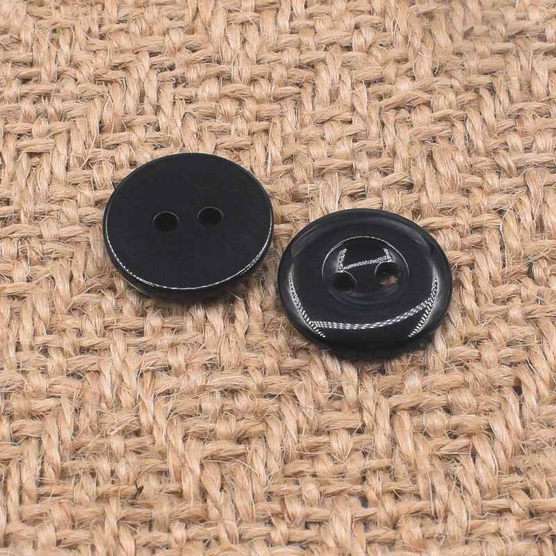 Round black 2-hole resin buttons, front view with glossy surface and stitched edge details