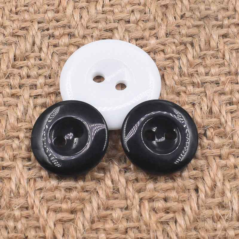 White round 2-hole resin button with two black 2-hole resin buttons, all glossy