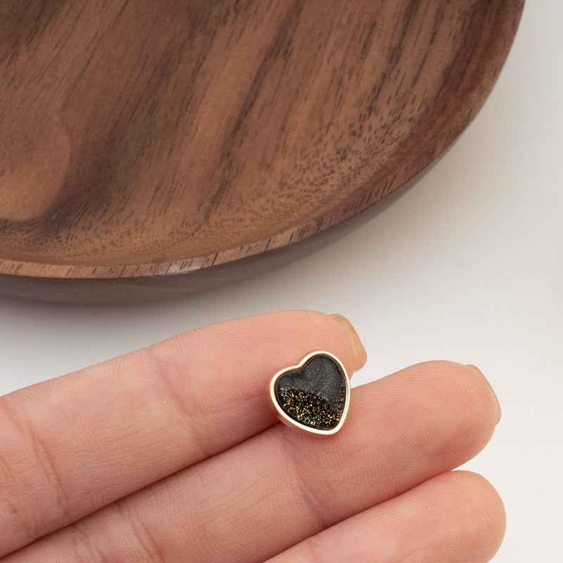 Heart-shaped button with dark iridescent center and gold-tone edge, close-up