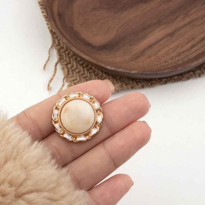 Black resin shank button with gold-tone ornate ring edge
