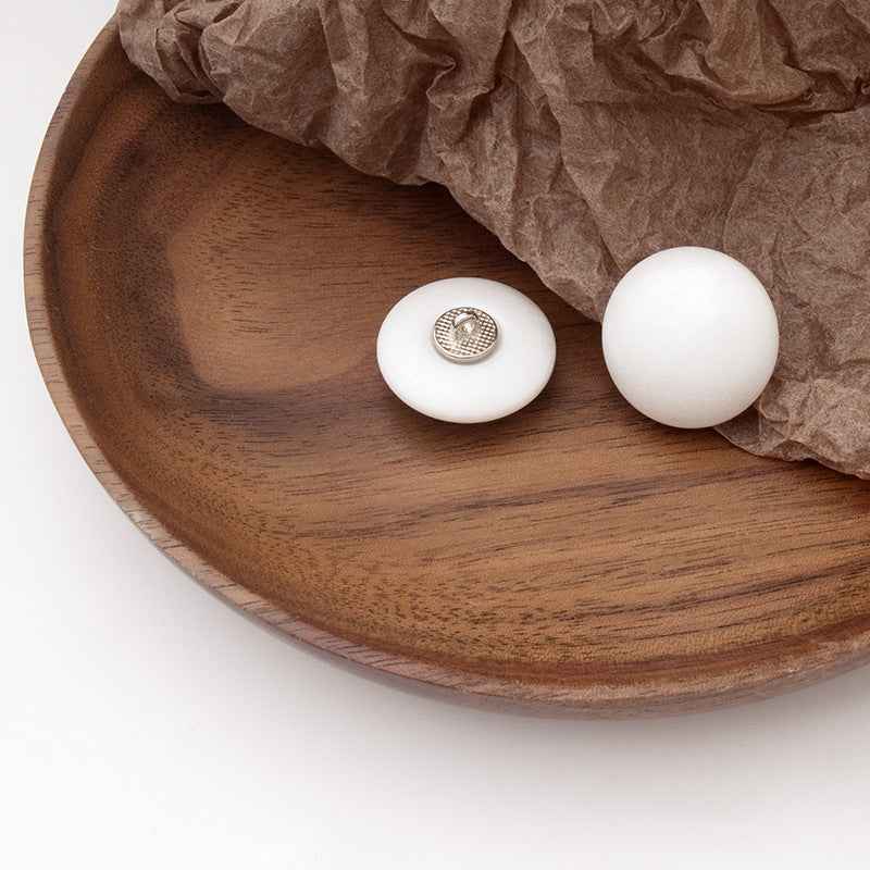 Two white round pearl buttons with metal shank, close-up of back plate