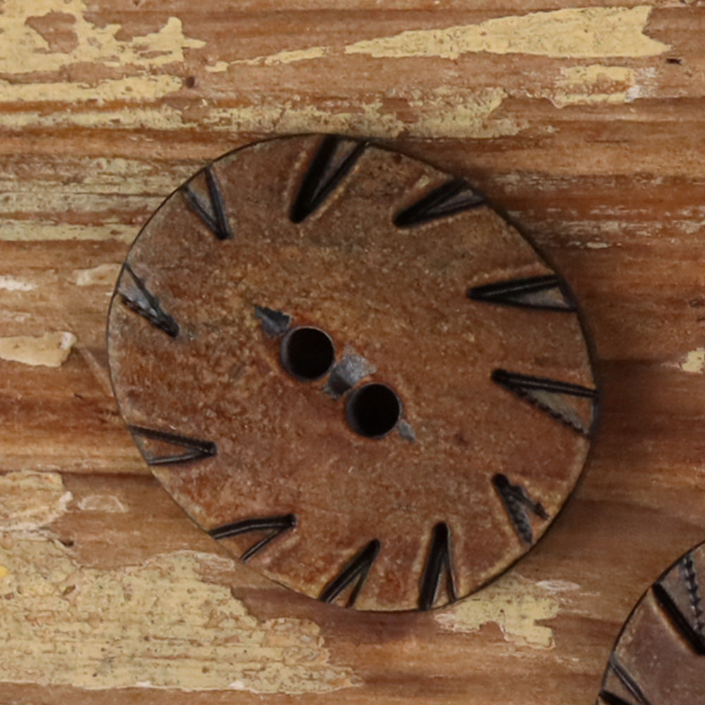 Oval two-hole horn button in grey with carved radial pattern and two holes.