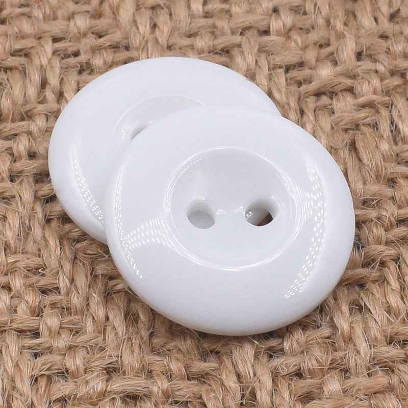 Round black 2-hole resin buttons, front view with glossy surface and stitched edge details