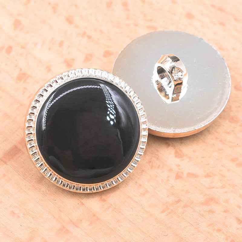 Black 21/23mm plastic shank button front with smooth glossy finish and silver textured border