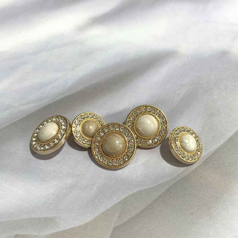 Round gold-tone buttons with rhinestone trim and beige centers, arranged flat