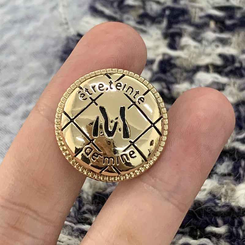 Gold circular metal M-letter button, engraved details with beaded border