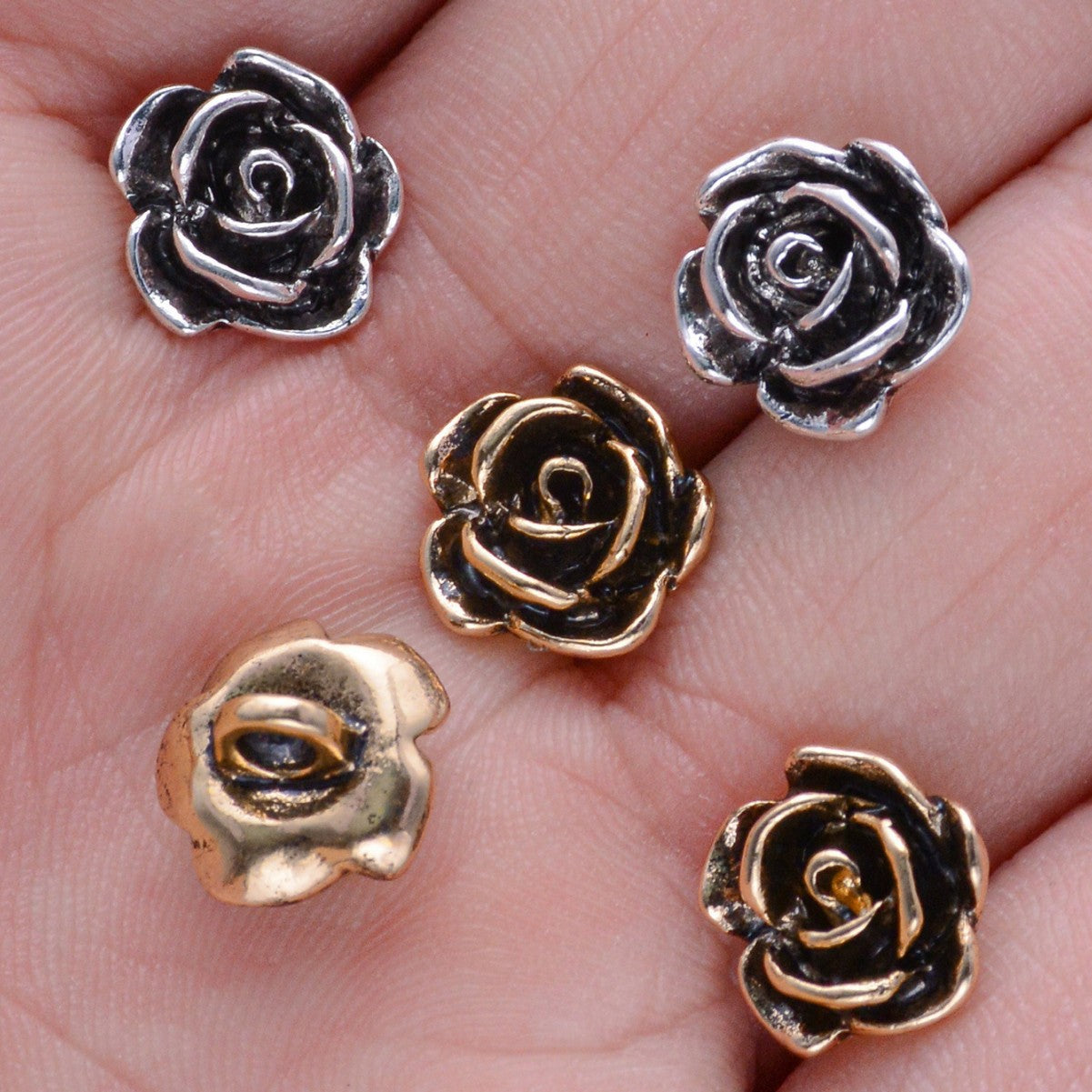 Rosenknöpfe in Silber und Gold mit Metallschlaufe auf der Hand
