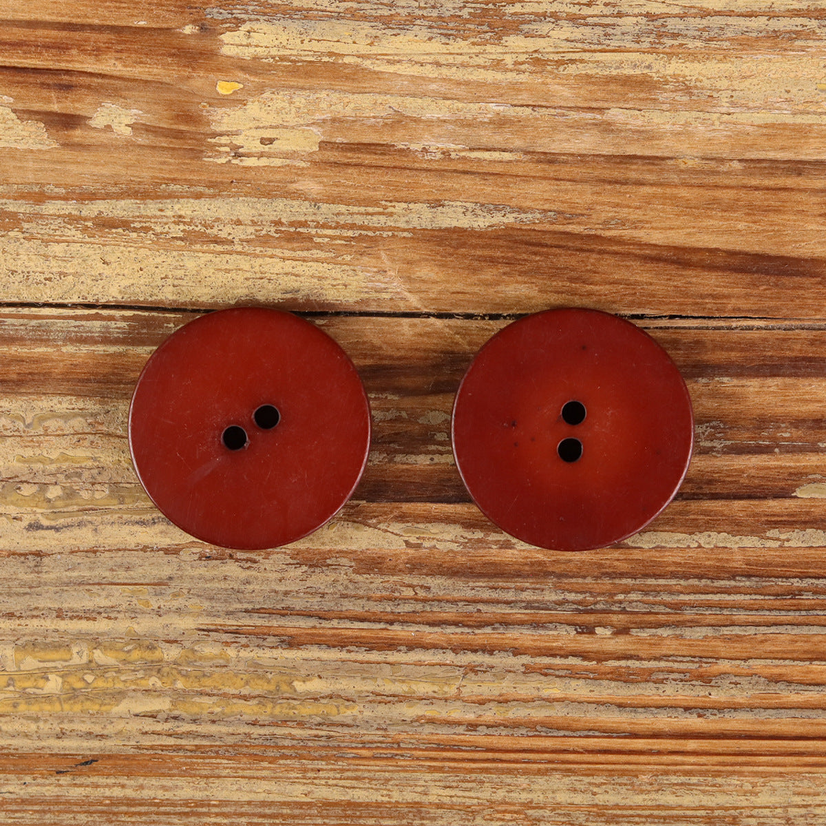 Set of 2 round red 2-hole buffalo horn buttons with natural speckled texture