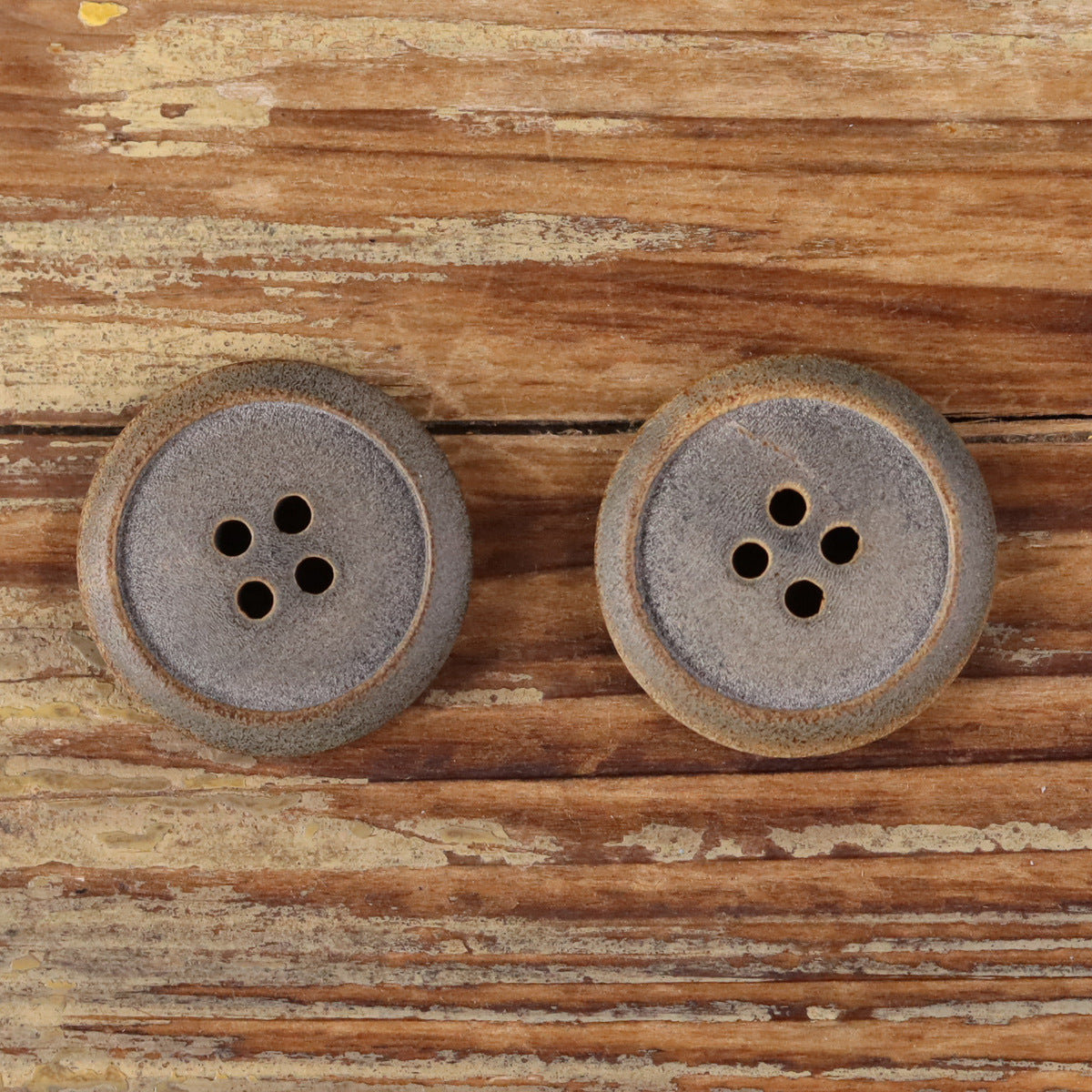 Pair of light gray matte buffalo horn buttons with burnt edges and four holes