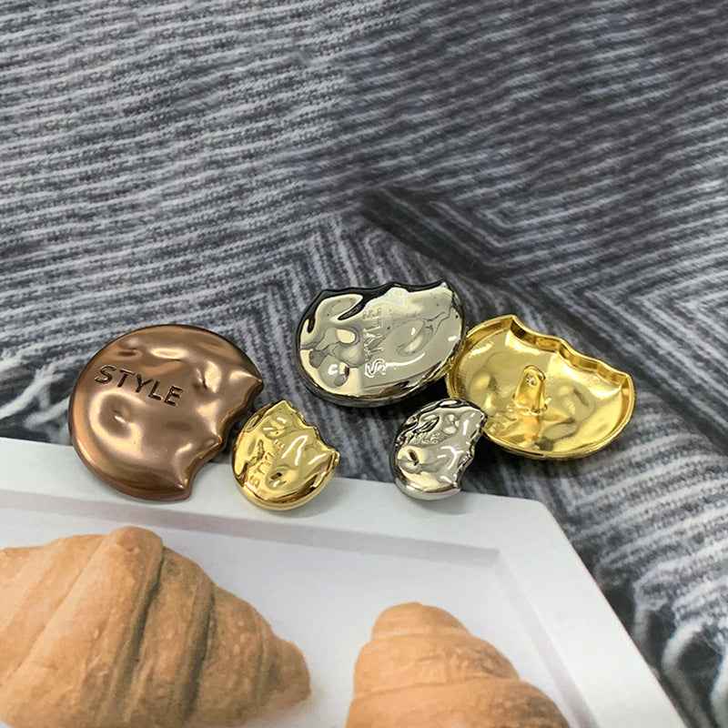 Assorted semi-circular metal shank buttons in coffee, gold, and silver with “STYLE”