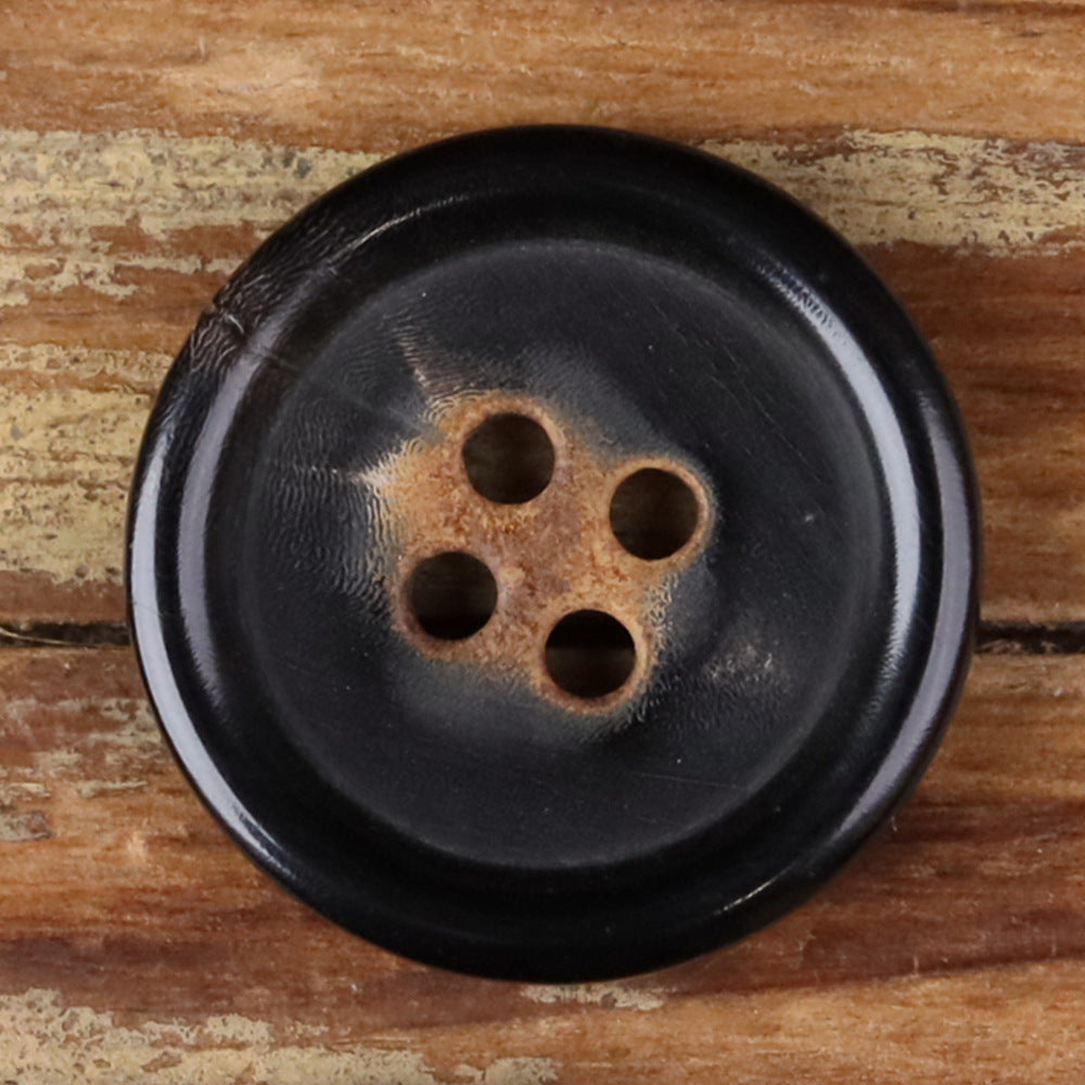Close-up of a 4-hole round button in dark tone with four holes